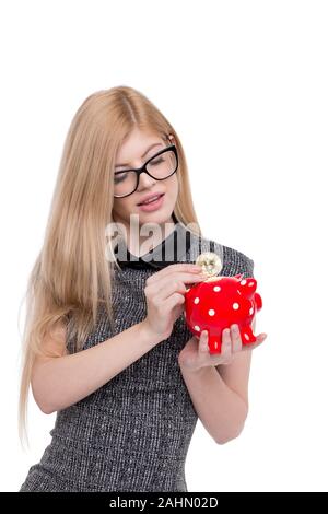 Blonde junge geschäftsfrau drop Bitcoin in roten gepunkteten Sparschwein, isoliert auf weißem Stockfoto