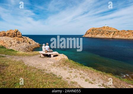 Ile-Rousse, Frankreich - 20. April 2016. Leute, die in der Bank und Pietra Insel Landschaft mit seinem Leuchtturm am Recht, Haute-Corse, Fran Stockfoto