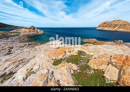 Pietra Insel Küste Landschaft in Ile-Rousse Stadt in Korsika, mit seinem Leuchtturm am Recht, rotem Porphyrstein Felsen Textur ist im Vordergrund, Haute-Corse Stockfoto