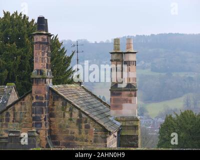 Die Schornsteintöpfe von Stanton Woodhouse ein Landhaus aus dem 16. Jahrhundert in der Nähe von Rowsley in Derbyshire mit Derwent Valley im Hintergrund am Wintertag Stockfoto