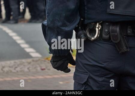 Riemen des Polizisten in schwarzen Uniform in Aktion, mit Handschellen, Baton und Gürteltasche. Stockfoto