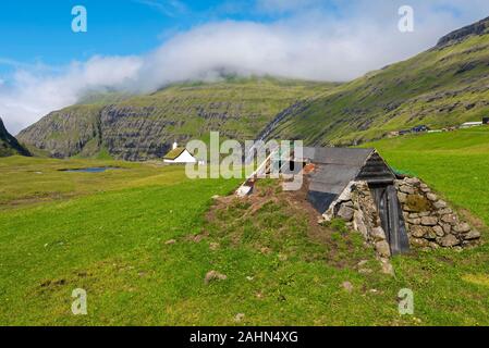 Grünland in der Nähe von Saksun Dorf der färöischen Insel Streymoy, der alte Bauernhof Konstruktion ist im Vordergrund Stockfoto