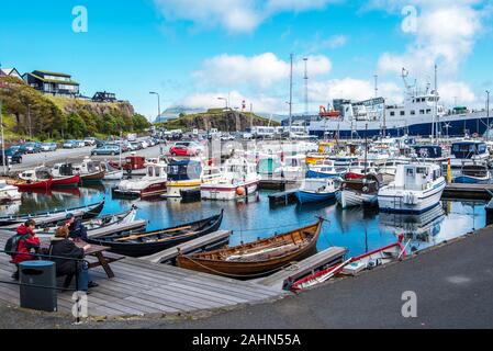 Tórshavn, Färöer - Juli 11, 2018 Menschen auf der Terrasse von Torshavn Hafen sitzen. Boote, Yachten und die Fähre in den Hafen, Skansin und stadt häuser Stockfoto