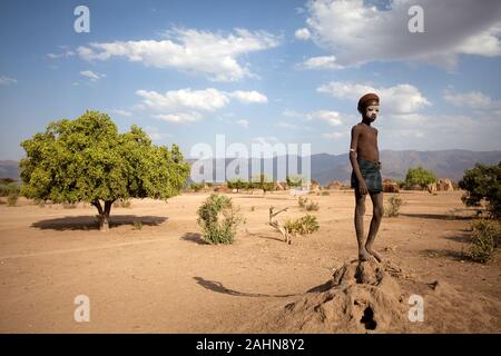 Traditionell bemalten Jungen von arbore Stamm stehend in trockener Umgebung des Omo Valley vor seinem Dorf, urige Hütten, Äthiopien, Afrika Stockfoto