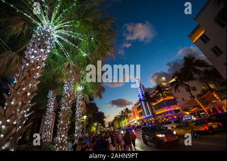 MIAMI - 30. Dezember 2018: die Touristen flanieren Sie die Lichter von Ocean Drive, mit dem Art déco-Neon und Urlaub Palmen mit Lichtern geschmückt Stockfoto