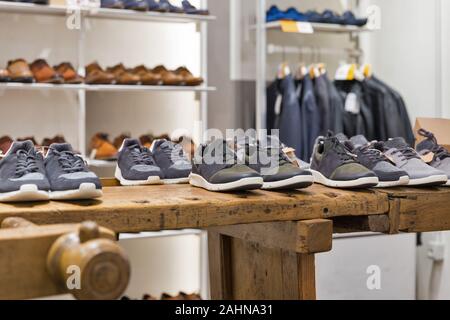 Anzeige der Schuhe auf hölzernen Regalen in der Moderne Männer Clothing Store Stockfoto