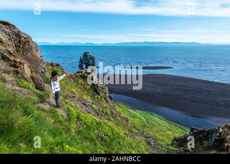 Mädchen Touristen Hvítserkur Basalt mit Wasser von hindisvik Bucht im Nordwesten von Island stack gewaschen. Es ist die Küste des Arktischen Ozean an E Stockfoto