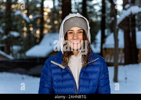 Ziemlich Hausberg Gemeinschaft jugendlicher Mädchen zeigt glückliches Lächeln im Gesicht, während warme Kleidung draußen im Schnee gekleidet abgedeckt Nachbarschaft. Stockfoto