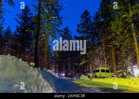 Schnee Banken angehäuft hoch nach dem Winter Schnee Sturm hat Fahrzeuge auf vereisten Straßen unter der Pine Tree Forrest und Star Sky gefüllt gefangen. Stockfoto