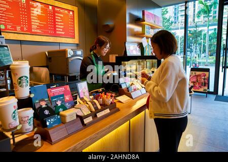 SHENZHEN, China - ca. Januar 2019: Frau kaufen Kaffee im Starbucks in Shenzhen. Stockfoto