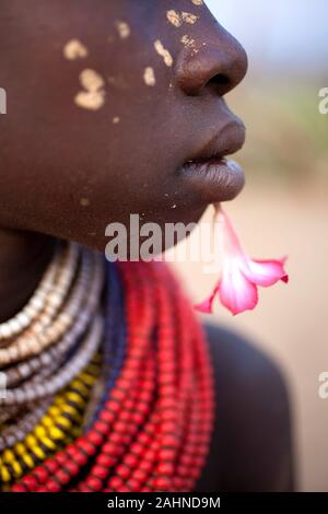 Mädchen aus Karo Stammes mit Blume in der Nähe von ihren Lippen und bemalten Wangen, Omo Valley, Äthiopien, Afrika Stockfoto