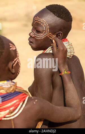 Junge Frauen aus der Karo Stammes Malerei jedes andere Gesicht mit traditionellen Muster, Omo Valley, Äthiopien, Afrika Stockfoto