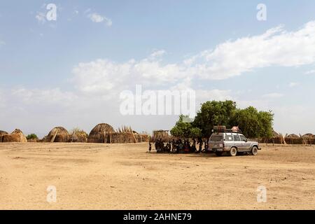 Touristenjep und Touristen interagieren mit Einheimischen im Schatten eines Baumes vor dem Arbore Viilage Lake turkana, der Grenze Äthiopiens und Kenias Stockfoto