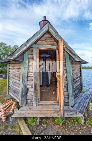 Schwedische Holz- Sauna mit Klappe öffnen, den Holzofen im Interieur gesehen, das Wasser des Gaxsjon See ist im Hintergrund. Jamtland County im nördlichen Schweden Stockfoto