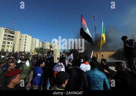 Bagdad. 31 Dez, 2019. Die Demonstranten versammelt sich vor der US-Botschaft in Bagdad, Irak zum 31.12.2019. Hunderte von Demonstranten, in der Trauer für die Hashd Shaabi Mitglieder durch US-Angriff im Irak getötet teilnehmen, stürmte die US-Botschaft in Bagdad Grüne Zone am Dienstag, eine amtliche Sicherheit sagte. Viele der Demonstranten, das Tragen von Uniformen Hashd Shaabi, sammelte, außerhalb der Botschaft Parolen verurteilen Luftangriffen der US-Streitkräfte gegen Hashd Shaabi Basen im Irak. Quelle: Khalil Dawood/Xinhua/Alamy leben Nachrichten Stockfoto