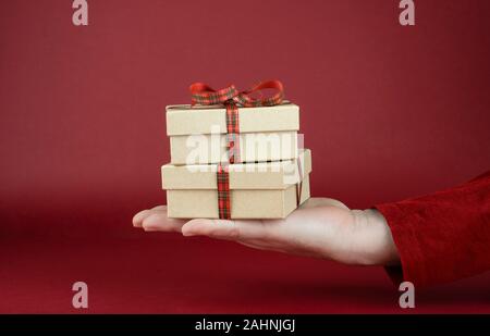 Des Menschen Hand Valentinstag Geschenk Boxen vor einem roten Hintergrund Stockfoto