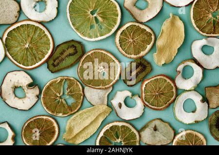 Orangen, Äpfel, Kiwis, Chips auf grünem Hintergrund. Bio vegan vegetarische Obst Snack oder Zutat für das Kochen. Getönten Bild. Ansicht von oben. Stockfoto