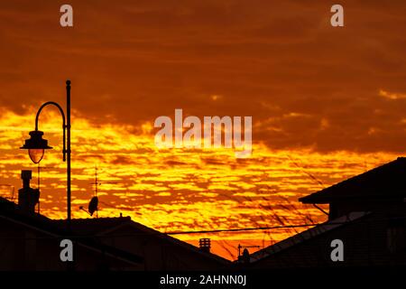 Schönen goldenen Sonnenuntergang über den Dächern eines toskanischen Dorf mit dramatischen Himmel Stockfoto