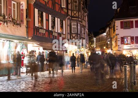 Käufer auf der Straße mit einer langen Verschlusszeit während der Weihnachtsmarkt im Elsass, Frankreich erfasst Stockfoto