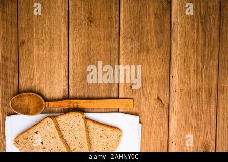 Vollkorn Toast auf weißen Serviette und Löffel aus Holz für das Mittagessen über Holz- Tabelle, Ansicht von oben, Kopieren, Mittag- Konzept Stockfoto