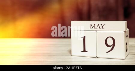 Kalender Reminder Veranstaltung Konzept. Holzwürfel mit Nummern und Monat am 19. Mai mit Sonnenlicht. Stockfoto