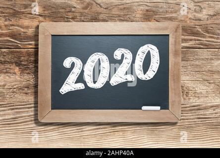 2020 auf Schiefer Kreidetafel gegen gealterten Holz Hintergrund geschrieben. Stockfoto