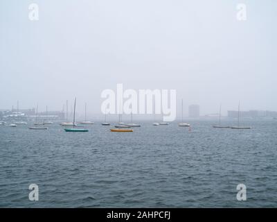 Kleine Segelschiffe vor Anker im Hafen von Boston an einem verschneiten Tag Stockfoto