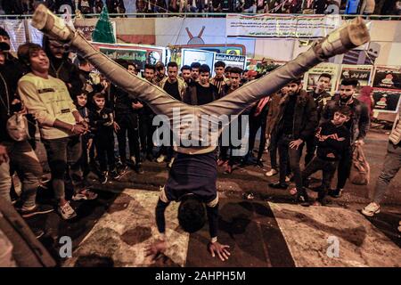 Bagdad, Irak. 31 Dez, 2019. Ein junger Mann führt einen handstand Tanz bewegen, während andere Sie sehen auf dem Tahrir Square, wo Menschen versammelt, die 2020 Silvester zu feiern. Credit: Ameer Al Mohmmedaw/dpa/Alamy leben Nachrichten Stockfoto