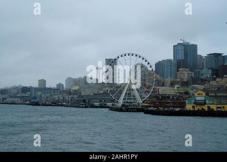 Blick auf die Innenstadt von Seattle, Washington Skyline von einem Fährschiff auf Elliot Bay; Seattle große Rad am Pier 57, Pier 56, verschwommenes Space Needle. Stockfoto