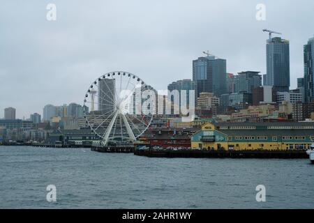 Blick auf die Innenstadt von Seattle, Washington Skyline von einem Fährschiff auf Elliot Bay; Seattle große Rad am Pier 57, Pier 56, verschwommenes Space Needle. Stockfoto