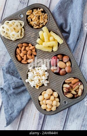 Eine Top-down-Sicht auf ein Muffin tin mit einer Vielzahl von verschiedenen gesunden Snacks gefüllt. Backwaren mit gesündere Entscheidungen austauschen. Stockfoto