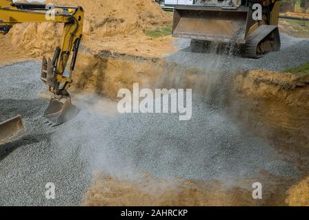 Nahaufnahme der Bagger auf einer Baustelle, Bagger Schaufel ebenen Kies in das Gebäude Stiftung Stockfoto