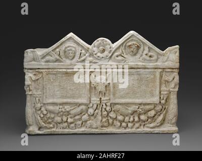 Antike römische. Cinerary Urn. 50 AD - 150 AD. Römische Reich. Marmor dieses cinerary urn wahrscheinlich hielt die verbrannten Überreste von zwei Personen, vermutlich ein Mann und eine Frau. Der Deckel ist mit Porträts des Verstorbenen durch Symbole der römischen Göttin der Liebe flankiert, Venus (der Griechischen Aphrodite), einschließlich Delphine und geflügelte erotes, mythologischer Begleiter der Göttin. Die Vorderseite der Urne enthält zwei rechteckige Platten, die für eine personalisierte Inschriften bestimmt waren, sondern leer gelassen. In der Umgebung des Panels sind Girlande Girlanden und einen Ochsen Schädel, beide Motive mit opferriten verbunden Stockfoto