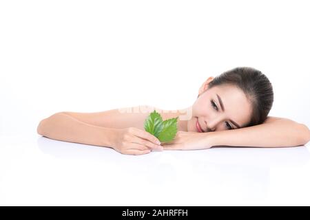 Close-up Studio shot, schöne junge Frau mit sauberem frische Haut Holding grüne Blätter. Ein Produkt vorschlagen. Gesten für Werbung auf Wh isoliert Stockfoto