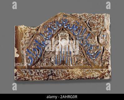 Iranische. Fliese Fragment mit Abbildung in einer Nische. 1265 - 1275. Persien. Fritware, Glanz lackierten gebrannte Glasur noch mal überglasieren Dekoration Diese Fliese ist einer der wenigen Fälle, in denen alle vier Hauptarten der Islamischen Ornamentik in einem einzigen Objekt verwendet werden. Vegetal Schriftrollen sind in verschiedenen Formen und Größen im Hintergrund des Stückes dargestellt; Kalligraphie läuft über die zentrale Arch; geometrische Muster vorhanden ist, auf das Kleidungsstück durch die zentrale Figur getragen; und figürlichen Darstellungen von Menschen und Tieren sowohl in der Person unter der Blende und band der laufenden Tiere an der Basis der Fliese Sitzen gefunden wird. Auch nicht Stockfoto