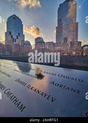 New York, USA - Dezember 14,2019: 9/11 Memorial mit weißen Blumen im Vordergrund und Wolkenkratzer im Hintergrund Stockfoto