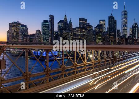 Skyline von New York von der Brooklyn Bridge bei Nacht Langzeitbelichtung Aufgenommen mit leichten Spuren von sich bewegenden Autos Stockfoto