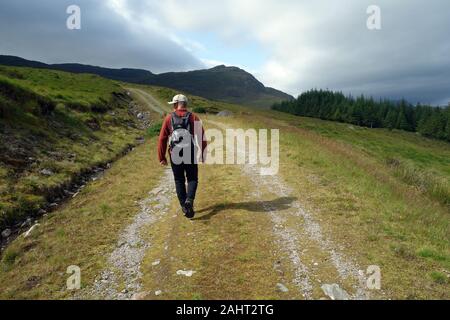 Einsame Mann zu Fuß auf dem Weg in den Millennium Windpark in die schottischen Berge Corbett Meall Dubh, Glen Moriston, Scottish Highlands, Schottland, Großbritannien. Stockfoto