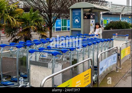 Weibliche air Traveller erhält ein Gepäck Trolley für Ihr Gepäck im Terminal 2, Flughafen Birmingham, West Midlands, UK. Stockfoto