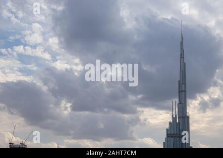 Burj Khalifa schließen oben mit bewölktem Himmel im Hintergrund. Seltene Wolkenbildung über UAE sky Stockfoto