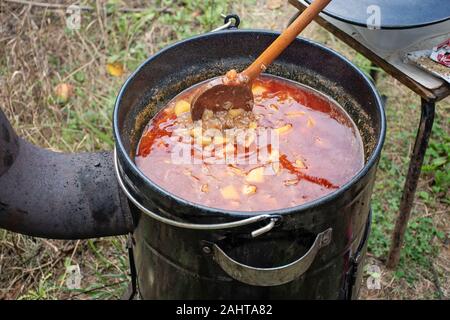 Kochen köstliches Kesselgulasch mit Treffen, Pfeffer, Tomaten, Zwiebel in einem großen Topf im Freien Stockfoto