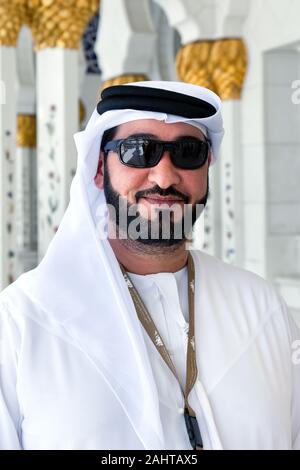 Arabische Geschäftsmann mit Sonnenbrille tragen kandora. Portrait von traditionellen emiratische Mann an der Großen Moschee von Abu Dabi Stockfoto