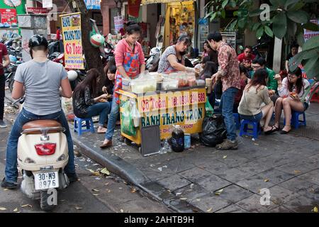 Asiatische Leute sitzen auf kleinen Stühlen essen ihr gemeinsames Mittagessen ein Fast-food-Anbieter Stockfoto