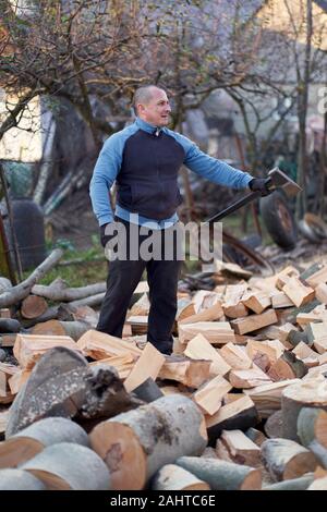 Ländliche Mann splitting Protokolle mit Axt und Maul in seinem Hinterhof Stockfoto