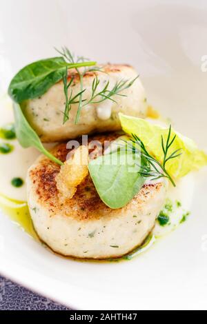 Lachs und Kabeljau Fisch Koteletts mit Spinat und Hecht Kaviar mit weißer Soße in einem Restaurant. Keto, Paleo, fodmap Diät essen. Close Up. Stockfoto