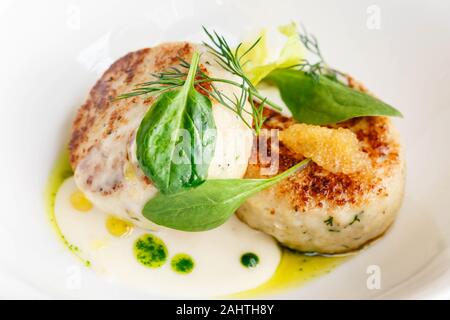 Lachs und Kabeljau Fisch Koteletts mit Spinat und Hecht Kaviar mit weißer Soße in einem Restaurant. Keto, Paleo, fodmap Diät essen. Close Up. Stockfoto