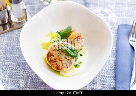 Lachs und Kabeljau Fisch Koteletts mit Spinat und Hecht Kaviar mit weißer Soße in einem Restaurant. Keto, Paleo, fodmap Diät essen. Close Up. Stockfoto