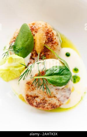 Lachs und Kabeljau Fisch Koteletts mit Spinat und Hecht Kaviar mit weißer Soße in einem Restaurant. Keto, Paleo, fodmap Diät essen. Close Up. Stockfoto