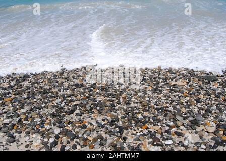 Ozean Waschen über mehrfarbige Beach Pebbles Stockfoto