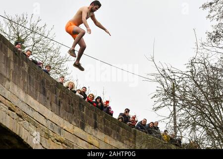 Eine Nächstenliebe, die Wettbewerber springt von der Okeover Brücke in den Fluss Dove während der mapleton raft Race und Brücke springen, in Mapleton, in der Nähe von Ashbourne, Derbyshire, als Teil der Tag des Neuen Jahres feiern. Stockfoto